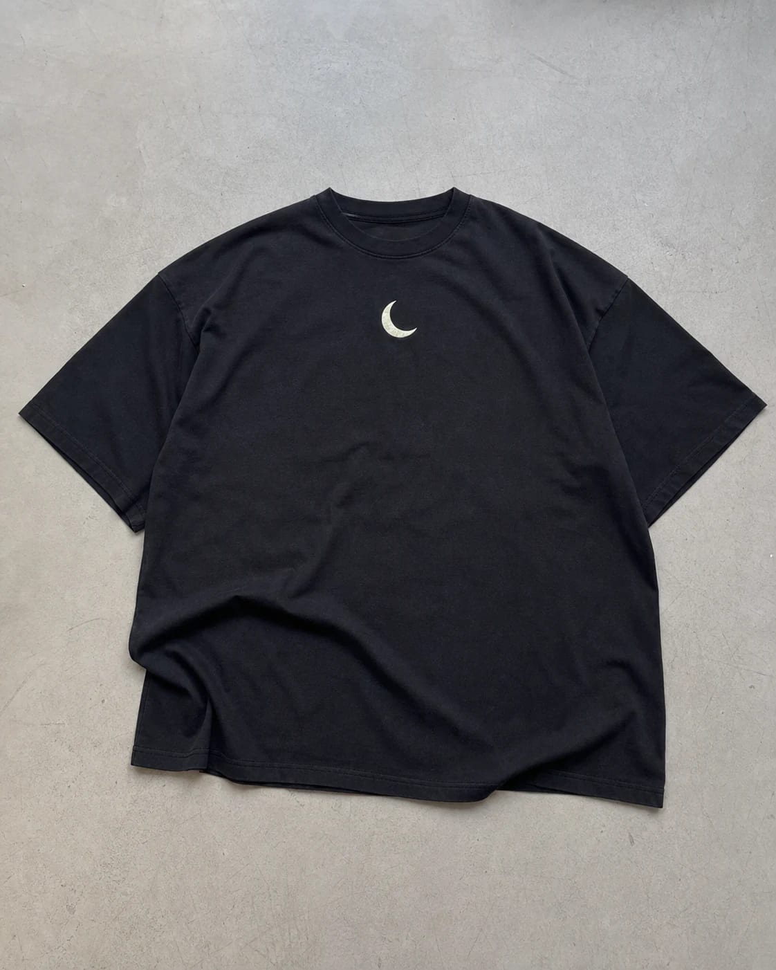 Black crescent T-shirt laid flat for a normal product photo